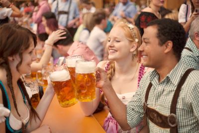 Oktoberfest: Drei Besucher prosten sich mit Masskrügen zu