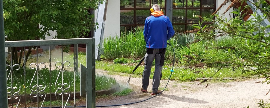 Ein Mitarbeiter vernichtet Unkraut auf öffentlichen Wegen - mit heißem Wasser.