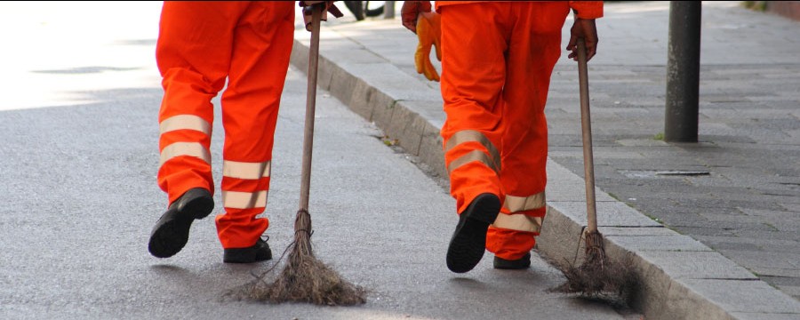 Arbeitspflicht: Zwei Arbeiter kehren die Straße.