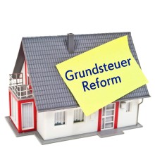 Haus mit Schild Grundsteuerreform auf dem Dach